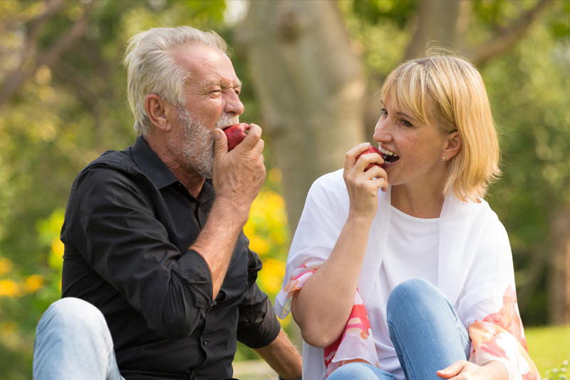 Dental Implant patients eating apples outside