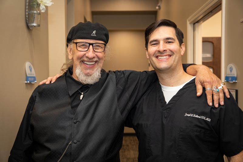 Dr. Holland smiling with arm around dental implant patient, Frank