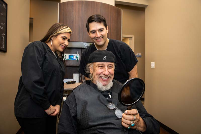 Dental Implant patient Frank loving his new smile as he glances in a mirror