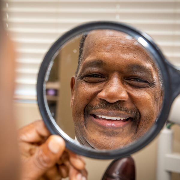 Dentures/Implant patient Eric smiling in the mirror